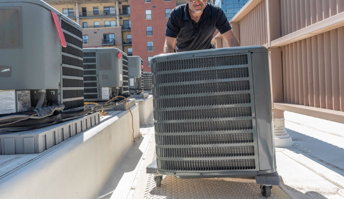 Person installing an air conditioning unit on a rooftop