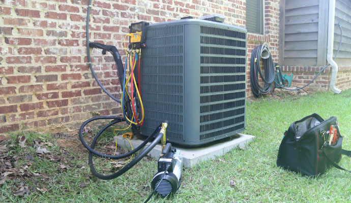 Outdoor AC unit on a concrete slab against a brick wall