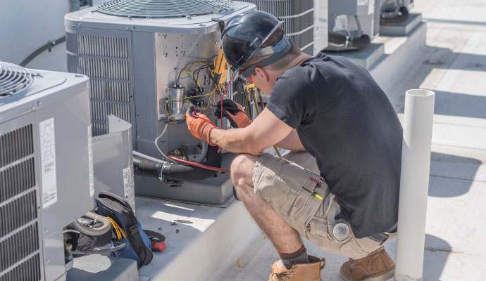 A technician working on an air conditioning unit outdoors.