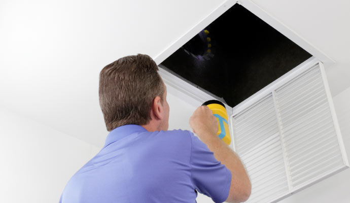 Professional inspecting air vent using flashlight