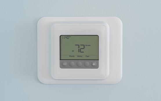 Smart thermostat on blue wall.
